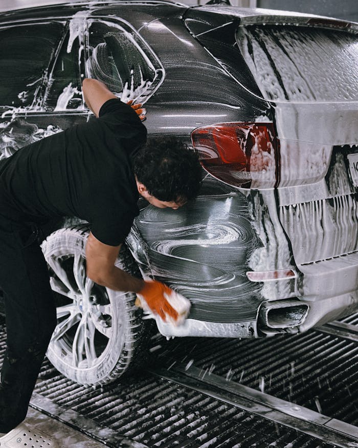 Mastering the First Impression: Your intriguing post title goes here A person meticulously washing a car at a car wash using soap and a sponge.