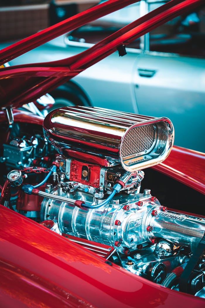 Detailed view of a chrome engine in a red classic car, showcasing engineering finesse.